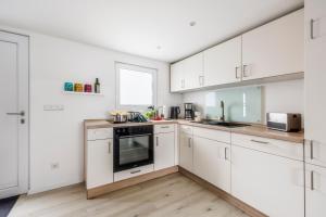 a white kitchen with white cabinets and a window at Ferienhaus Waldgeflüster 70 QM I überdachte Terrasse I 2 Schlafzimmer I Strandnah in Joachimsthal
