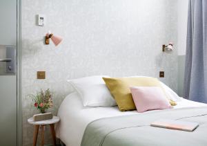 Un dormitorio con una cama blanca con almohadas rosas y amarillas en Hôtel Henriette en París