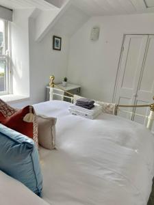a large white bed in a room with a window at Homestead in Port Isaac