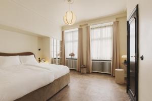 ein Schlafzimmer mit einem großen Bett und zwei Fenstern in der Unterkunft Hotel Bella Grande in Kopenhagen
