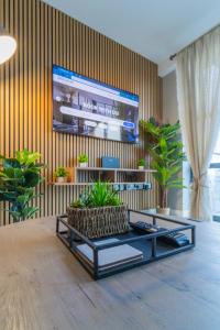 a living room with a tv on a wall with plants at Belfast Quarters: 9th floor Gem! in Belfast