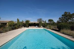 una piscina en un patio con 2 sillas blancas en Air-conditioned Provençal farmhouse with private pool, view magnificent, located in Lagnes, close Isle S/Sorgue, 9 people, en Lagnes