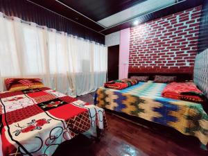 um quarto com 2 camas e uma parede de tijolos em Narayan valley resrot & hotel Sonparyag em Trijugi Nārāyan