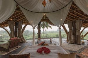 a bedroom in a tent with a bed with flowers on it at Camaya Bali - Magical Bamboo Houses in Selat