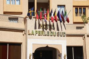 Ein Schild für ein Hotel mit vielen Flaggen in der Unterkunft Hotel La Perle du Sud in Ouarzazate