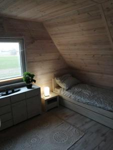 Cette petite chambre comprend un lit et une fenêtre. dans l'établissement "Morze Spokoju" domki letniskowe, à Darłówko