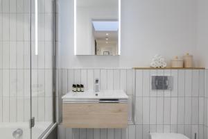 a white bathroom with a sink and a mirror at Urban Chic - Marine in London