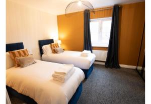 Duas camas num quarto com uma janela em Black Pearl Stays - 3 bedroom house with hot tub - Linthorpe, Middlesbrough em Middlesbrough
