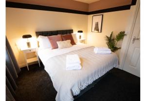 a bedroom with a large white bed with towels on it at Black Pearl Stays - 3 bedroom house with hot tub - Linthorpe, Middlesbrough in Middlesbrough