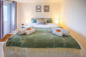una camera da letto con un grande letto con due cuscini sopra di The Den by StayStaycations a Rugeley