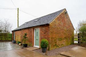 a small brick building with a green door at The Den by StayStaycations in Rugeley