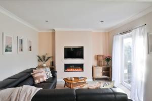 sala de estar con sofá de cuero negro y chimenea en Cloudbreak Braunton North Devon en Braunton