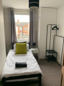 a bedroom with a bed with a yellow pillow and a window at Dunhill Townhouse in Goole