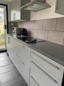 a kitchen with white cabinets and a black counter top at Dunhill Townhouse in Goole