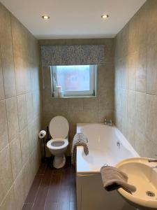 a bathroom with a tub and a toilet and a sink at Dunhill Townhouse in Goole