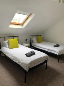two beds with yellow pillows in a room at Dunhill Townhouse in Goole