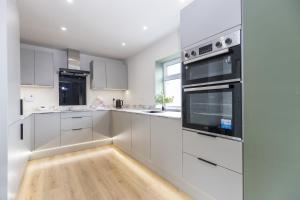 a kitchen with white cabinets and black appliances at H C Property - Doublegait in Barnard Castle