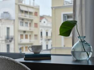 un vase en verre avec une plante et une tasse sur une table dans l'établissement RESIDENCE PATRAS, à Patras
