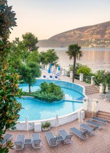 a swimming pool with chairs and a body of water at Hunguest Hotel Sun Resort in Herceg-Novi