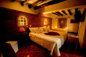 a bedroom with a bed and a brick wall at Hotel Los Frayles in Villa de Leyva