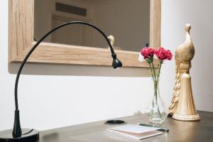 einen Schreibtisch mit einer Lampe und einer Vase aus Blumen in der Unterkunft Curzon Residences in London