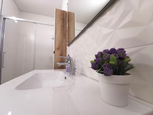 een badkamer met een wastafel en een vaas met paarse bloemen bij Locazione La Scacchiera in Padua