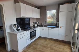 a kitchen with white cabinets and black appliances at Alpenpanorama Oase in Feldkirch