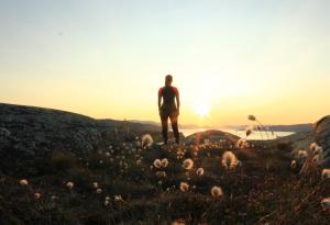 a man standing on a hill watching the sunset at Sorrisniva Arctic Wilderness Lodge in Alta