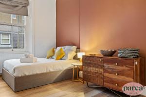 伦敦Parea Living - South Kensington, Elegant 1-Bedroom Flat, WFH Desk的带床、梳妆台和窗户的卧室
