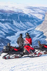 two people riding on a snowmobile in the snow at Sorrisniva Arctic Wilderness Lodge in Alta