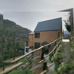 a brick house with a metal roof on a hill at Gülhan Butik Hotel & Bungalov in Rize
