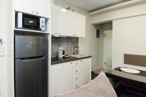 a kitchen with white cabinets and a black refrigerator at Stylish Athinas House in Kallithea in Athens