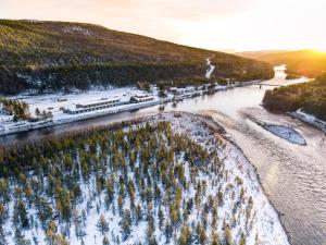 an aerial view of a river with snow and trees at Sorrisniva Arctic Wilderness Lodge in Alta