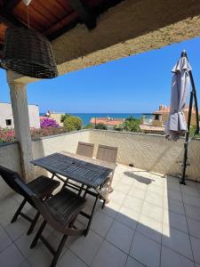 a patio with a table and chairs and an umbrella at RESIDENCE LA PLAGE Pieds dans l'eau Belle Vue mer in Linguizzetta +6 photos