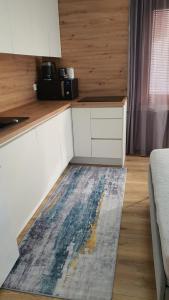 a kitchen with white cabinets and a rug on the floor at Apartment Noah in Sarajevo