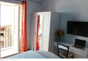 um quarto com uma cama, uma secretária e uma janela em Il riad del capitano em Siracusa