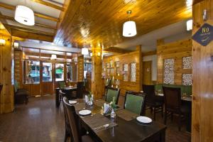 a restaurant with wooden walls and tables and chairs at The Whispering Inn Resort and Bar (An Exotic Vintage Beauty ) in Manāli