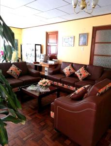 a living room with brown leather couches and a table at Bello departamento independiente in La Paz