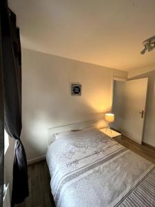 um quarto com uma cama branca num quarto em Le coin cosy 38 m2 em Orchies