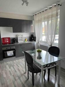 uma cozinha com uma mesa de vidro e cadeiras numa cozinha em Le coin cosy 38 m2 em Orchies