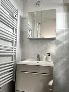W białej łazience znajduje się umywalka i lustro. w obiekcie Le coin cosy 38 m2 w mieście Orchies