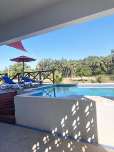 a swimming pool with two chairs and an umbrella at The Tiki Toucan Tropical Suite + Private Pool in Placencia Village