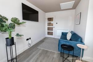 uma sala de estar com um sofá azul e uma televisão em Modern & stylish 1 bed, 10 min to beach and town, parking - Just Beachy em Bournemouth