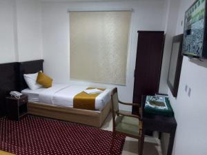 a small bedroom with a bed and a chair at فندق ملتقي الإيمان للضيافة السياحي in Makkah