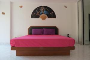 ein Bett mit einer rosa Tagesdecke und einem Bild an der Wand in der Unterkunft View Talay 1 Jomtien in Pattaya South
