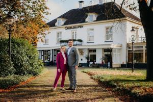 a man and a woman standing in front of a building at Landgoed Hotel & Restaurant Carelshaven in Delden