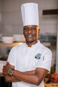 un chef parado en una cocina con los brazos cruzados en Cap Kivu Hôtel, en Goma