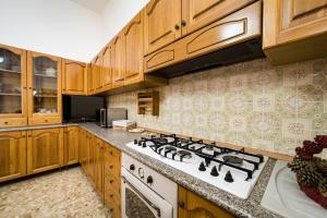 eine Küche mit Holzschränken und einem weißen Herd mit Backofen in der Unterkunft Villetta Iris by Vivimy in Taviano + 25 Fotos