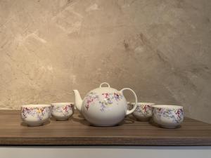a tea pot and four cups on a wooden shelf at Bachmanns Ferienwohnung in Schotten