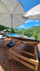 une terrasse en bois avec un parasol et une piscine dans l'établissement House Mint, à Matulji